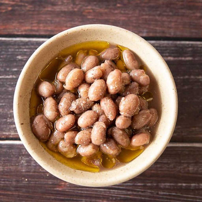 Bowl of beans with oil on a wooden surface