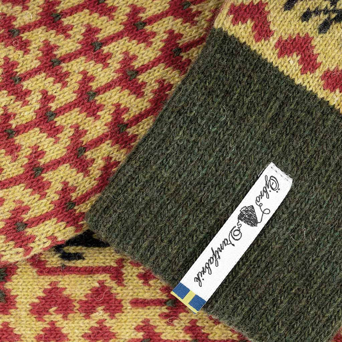 Green fabric on a patterned yellow and red fabric background with a label.