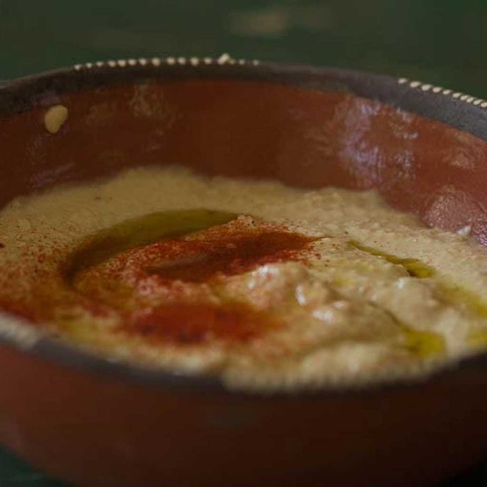 Close-up of a bowl with hummus on a dark background