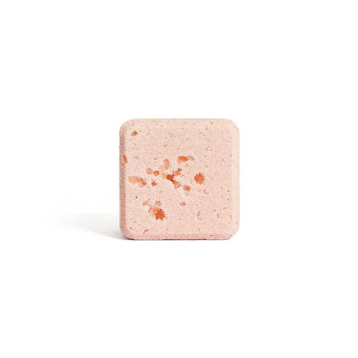 Square pink bath bomb with orange specks on a white background