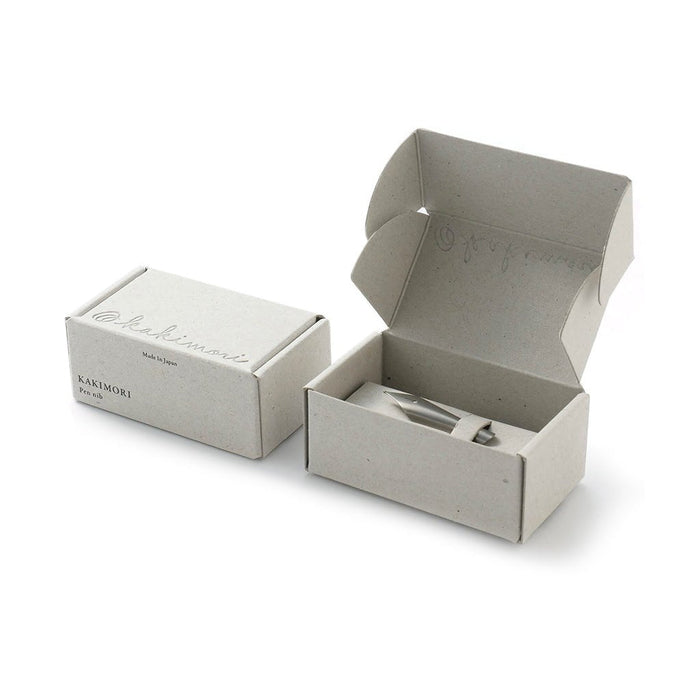 Open beige box with a smaller box and pen nib inside on a white background