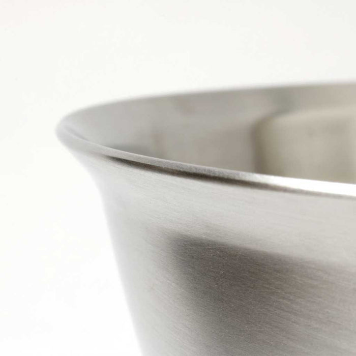 Close up of rounded edge of stainless steel bowl on white background