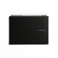 A black spiral-bound notebook with gold foil text reading '183 | Mnemosyne' on the cover.