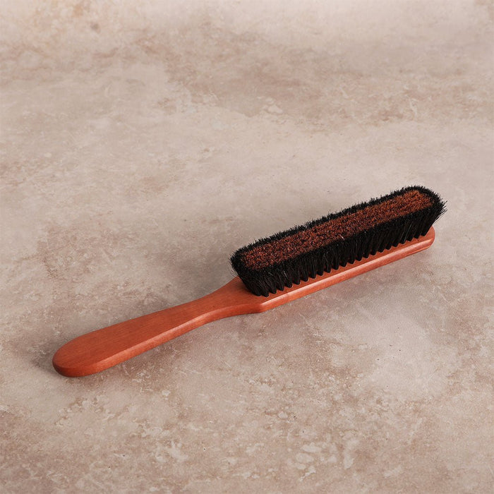 Wooden clothes brush with bronze wire laying on light surface